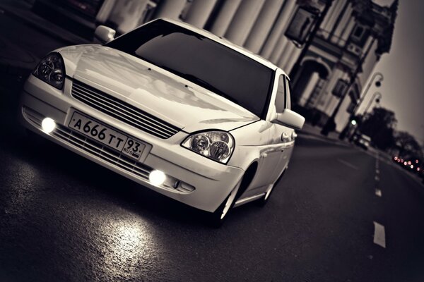 VAZ Lada Priora white stands on the road near a beautiful building