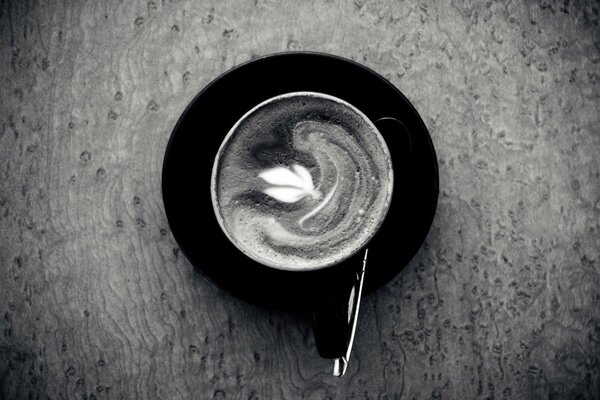 Schwarz-Weiß-Foto einer Kaffeetasse mit Untertasse und Löffel