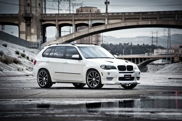 A white BMW crossover stands against the background of the bridge