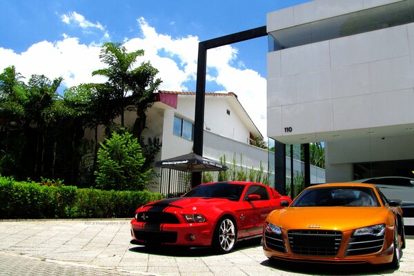 White, orange and red cars on the background of the house