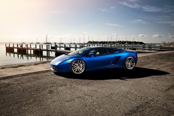 Blue Lamborghini on the dock next to the yacht