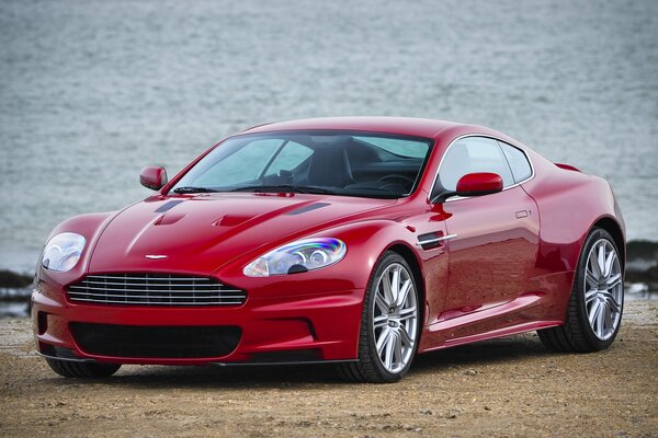 Aston Martin rouge sur la plage de sable