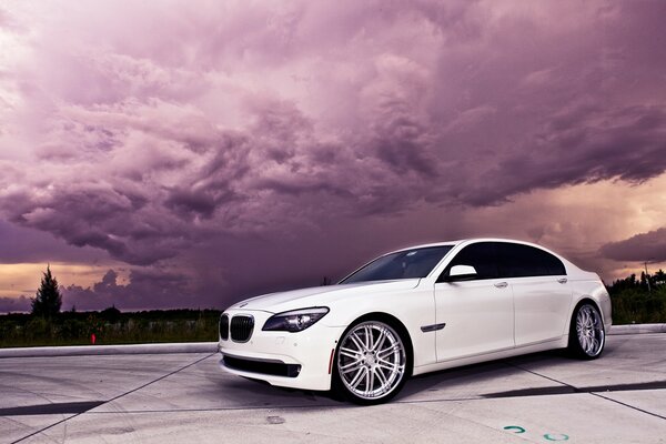 Elegante BMW blanco contra el cielo púrpura y las nubes