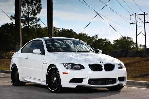 BMW blanco en la carretera en el fondo de las líneas de transmisión