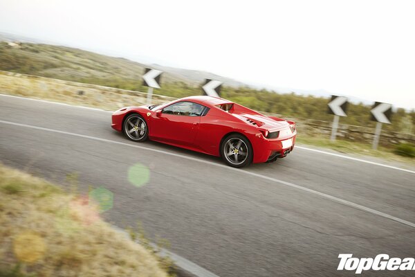 Auto sportiva rossa che corre su una strada di montagna