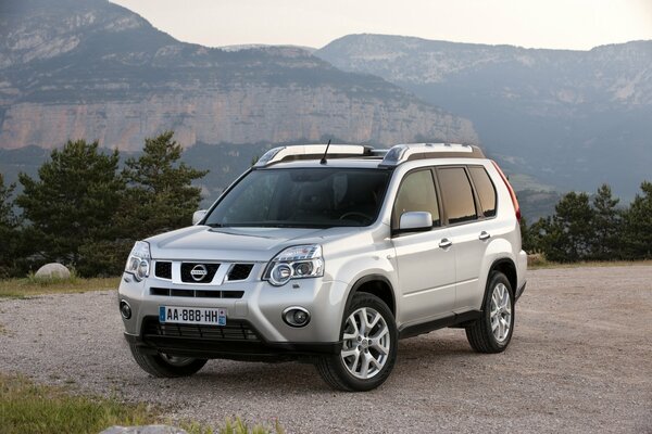 SUV nissan x-trail sullo sfondo delle montagne