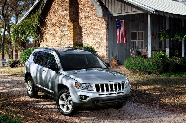 A silver jeep at a brick house