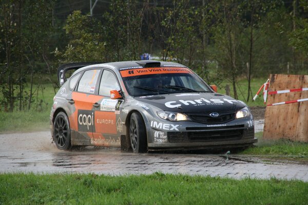 Voiture de sport participant au rallye avec de la boue et de la pluie sur fond de forêt verte et de l herbe dans la journée