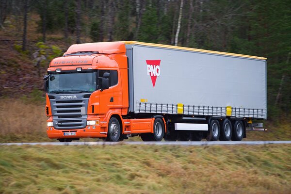 A huge Scania truck is driving on the road