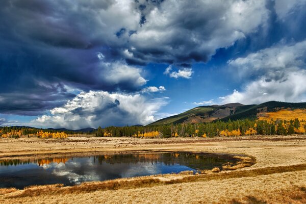 See mit Wald, Bergen und Wolken