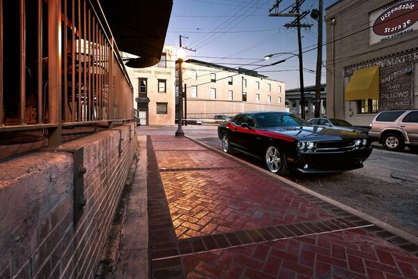 A black Challenger car is parked at the curb