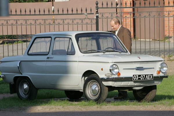 Präsident Putin steht in der Nähe des grauen Zaporozhets und lächelt