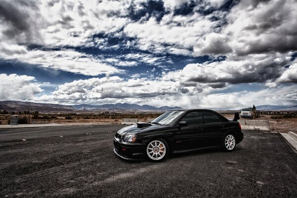 Black subaru on a cloudy sky background