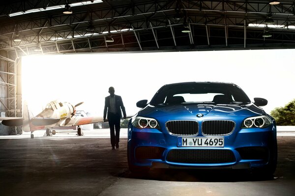 Blauer bmw m5 steht im Hangar für Flugzeuge