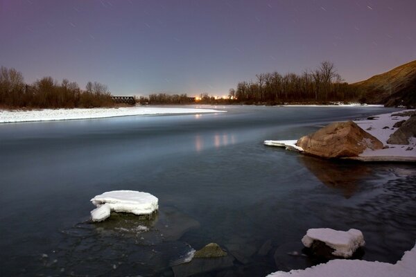 Winter am Fluss mit Schnee und Steinen