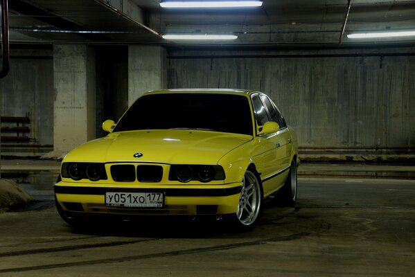 Bmw E34 jaune dans un parking souterrain