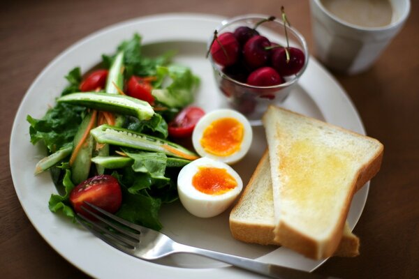 Breakfast of eggs, toast and salad on a white plate