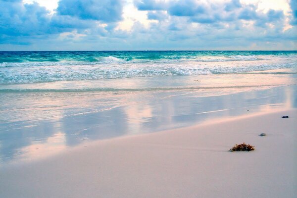 Wellen des Meeres vor dem Hintergrund des Strandes und der Wolken