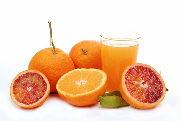 Naranjas y pomelos junto a un vaso de jugo de naranja