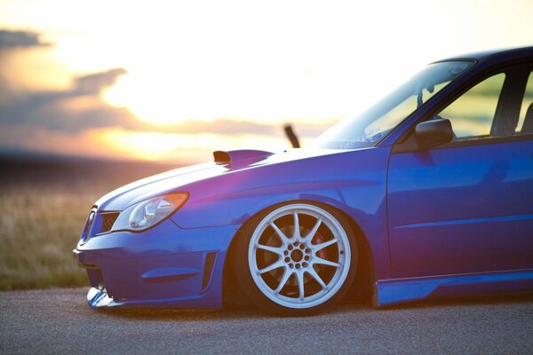 A bright blue car is driving on the road