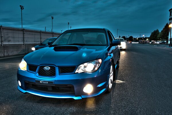 Coche azul Subaru por la noche en la carretera