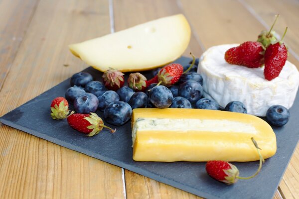 Käse neben Blaubeeren und Erdbeeren auf einer Serviette