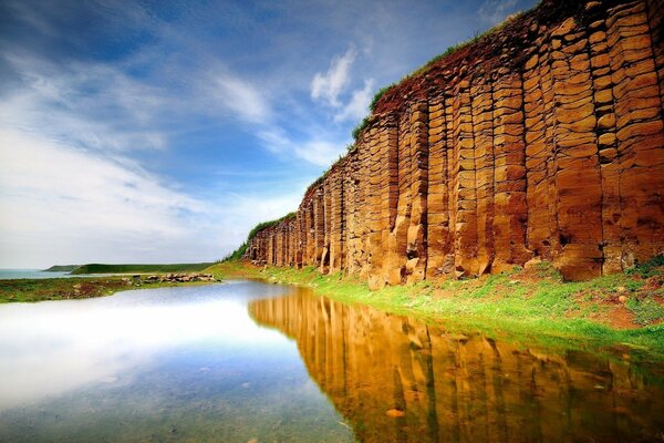 Enorme roca pelirroja al lado del lago