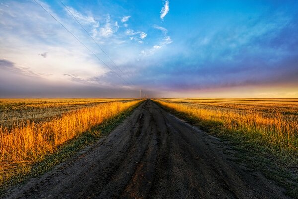 El camino en el campo en el fondo de un hermoso cielo