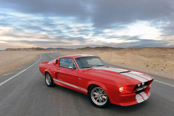 A classic car. the red car is alone on the highway