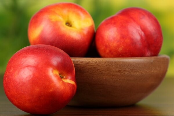 Three apples in a wooden bowl