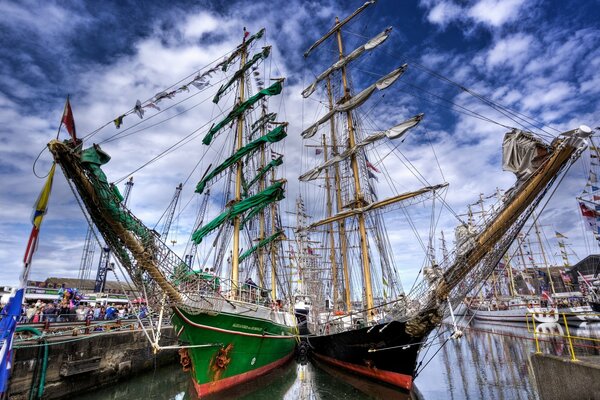 Yates con velas verdes y blancas en el muelle