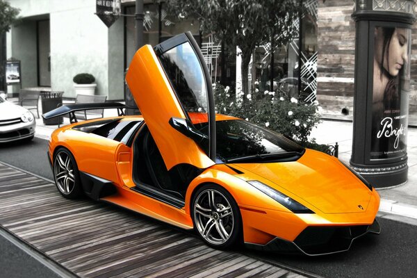 Orange Lamborghini with an open door on a gray street