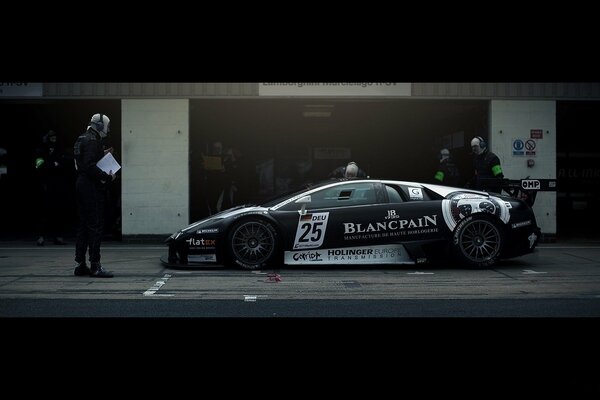 Une supercar noire avec spoiler s est arrêtée au pit Stop