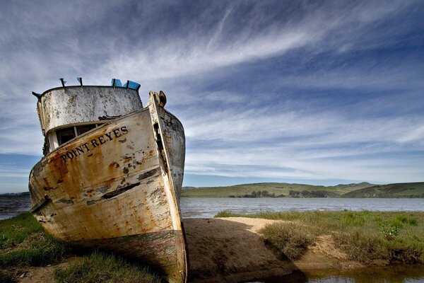 Un viejo barco en la orilla bajo el cielo azul