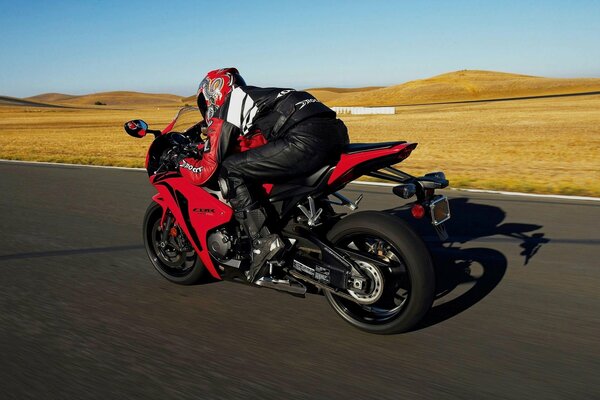 A motorcyclist in a protective suit and helmet, racing along the track on a sport bike