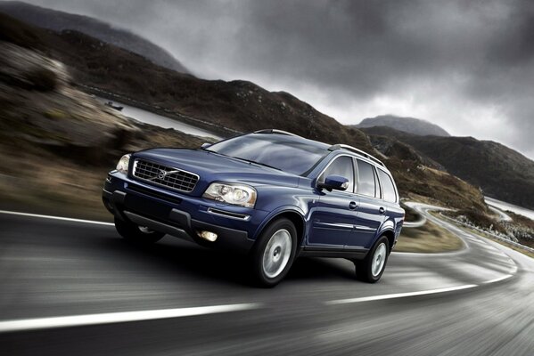 Une Volvo bleue roule sur une route déserte