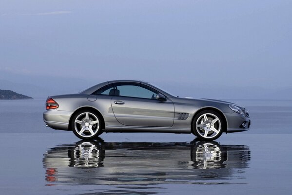 The gray car is reflected in the water