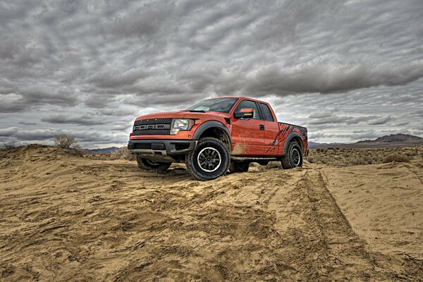 Red Ford car on the background of a dirty road