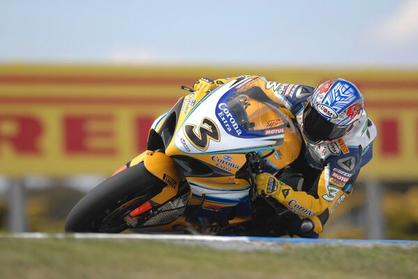 A motorcyclist on a yellow motorcycle entering a turn