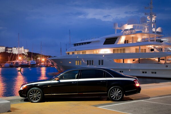 Luxury black car on the background of a large white yacht