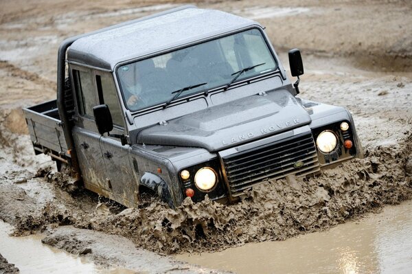 An off-road car is moving through the mud