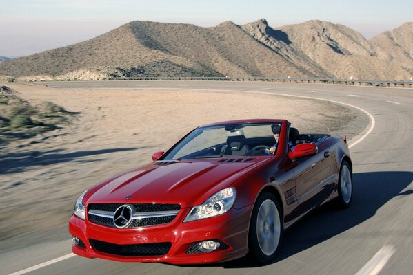 Voiture rouge sur la route entre les barkhans