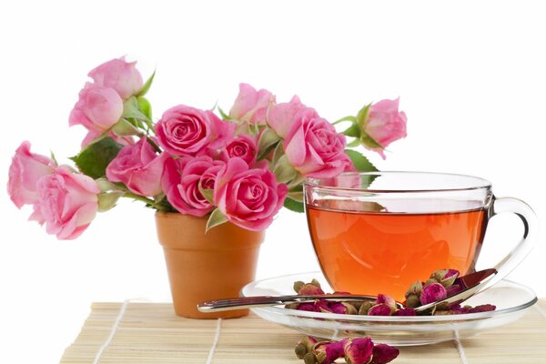 Un ramo de rosas y una taza de té en un platillo decorado con capullos de flores