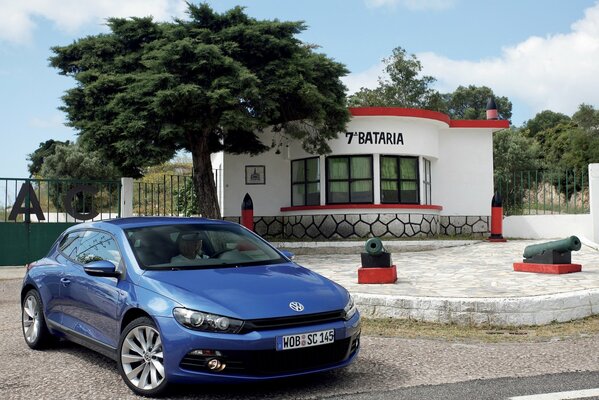 A blue Volkswagen is parked near the house