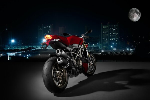 A red Ducati motorcycle stands at night against the background of the city