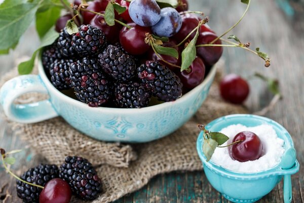 Naturaleza muerta con moras y cerezas en un tazón azul