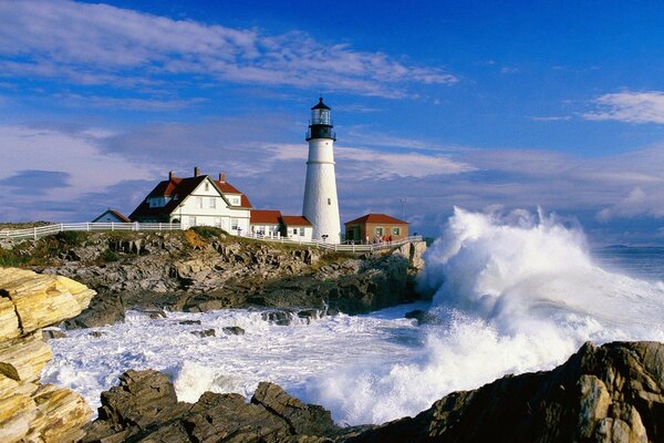 A stone cliff, the crest of a wave, stands on a cliff lighthouse and houses