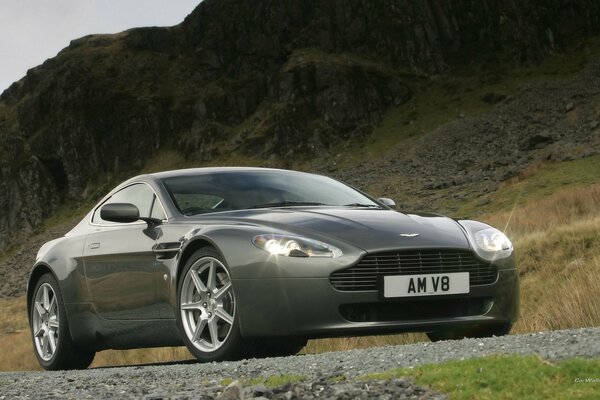 Un Aston Martin V8 gris en medio de las montañas