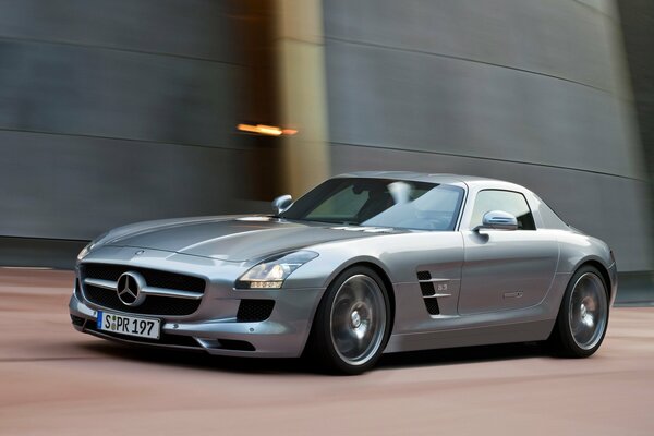 Silver Mercedes on the road under a concrete wall