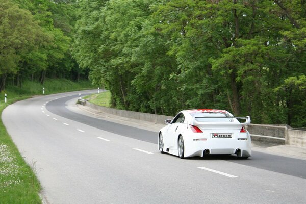 En la carretera conduce un hermoso coche blanco